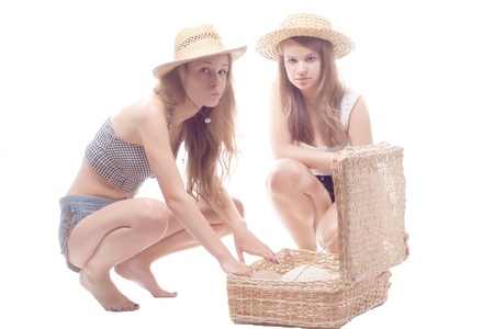 Two girls in straw hats with a straw suitcase, studio photographyの写真素材