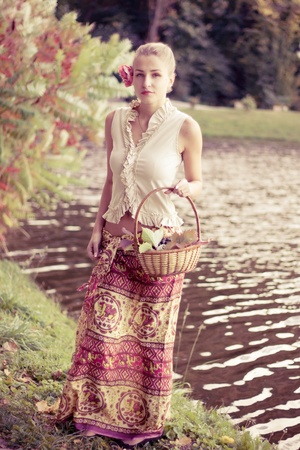 Beautiful girl in a long skirt with a basket of grapes outdoors shootingの写真素材