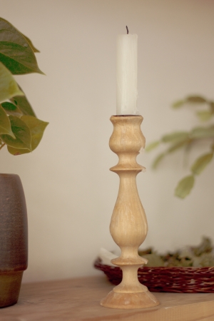 Long white candle in a wooden candlestick on the shelfの写真素材