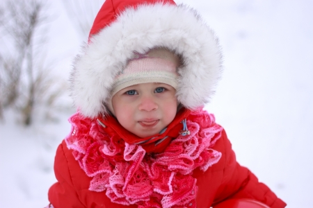 Beautiful baby playing on snow in winterの写真素材