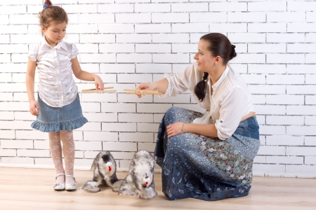 Mother and 5 year old daughter playing with two toy dogsの写真素材