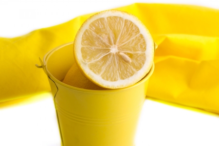 Lemons are in a yellow bucket near napkinsの写真素材