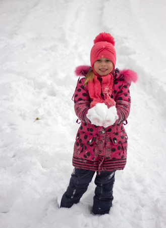 Little girl in winter pink hat in snow.の写真素材