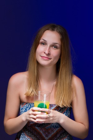 Beautiful girl drinking a cocktail against blue backgroundの写真素材