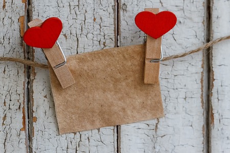 Note on the background of an old fence with clothespins in a heart shape