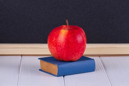 Red apple on old mini book against blackboard with space for text. School conceptの写真素材