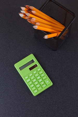 Pencils in the stand and the calculator on a black background. The view from the topの写真素材