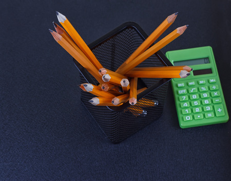 Pencils in the stand and the calculator on a black background. The view from the topの写真素材