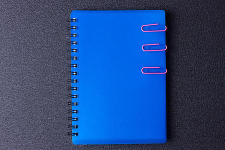 Blue notepad with paper clips on a black backgroundの写真素材