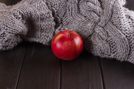 Red apple in a knitted gray sweaterの写真素材