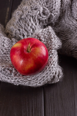 Red apple in a knitted gray sweaterの写真素材