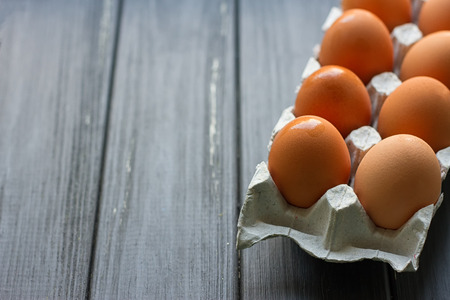 Cardboard egg box on black wooden background. Eggs container
