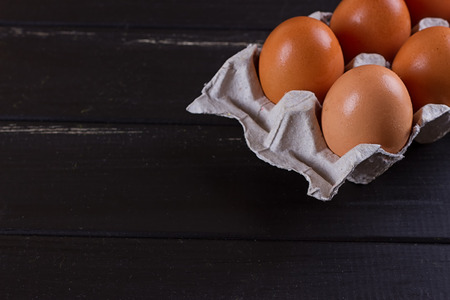 Cardboard egg box on black wooden background. Eggs containerの写真素材