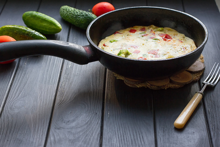 Breakfast set. Pan of fried eggs with fresh tomato, cucumber, sage on dark serving board over black backgroundの写真素材