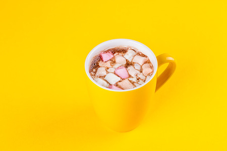 Yellow cup of hot cocoa with marshmallows on yellow backgroundの写真素材