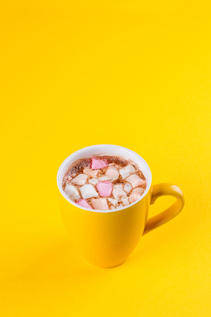 Yellow cup of hot cocoa with marshmallows on yellow backgroundの写真素材