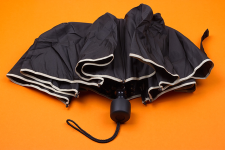 closed black umbrella on the orange backgroundの写真素材