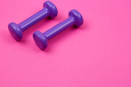 Purple dumbbells on a pink background, minimalist concept, top viewの写真素材