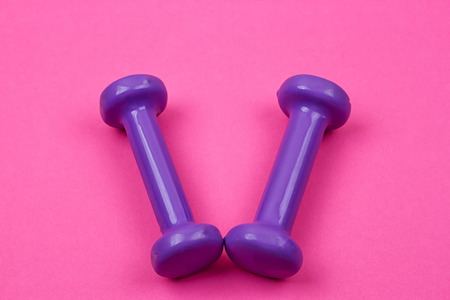 Purple dumbbells on a pink background, minimalist concept, top viewの写真素材
