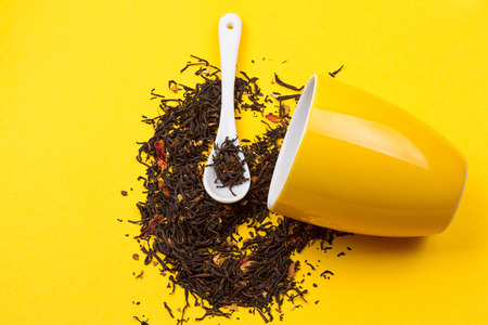 Falling driedn teain cup on yellow background white backgroundの写真素材
