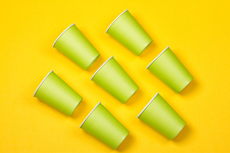Set of green paper cups on a yellow background