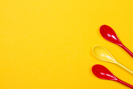 Set of multi-colored long spoons on a yellow backgroundの写真素材