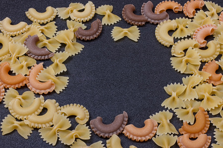 Variety of types of Italian pasta background. Set of raw dry pasta on a black slate background.の写真素材