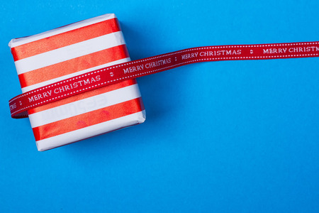 Gift in red and white packing with ribbon on a blue background. a Christmas giftの写真素材