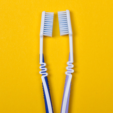 twi Toothbrushes on the yellow background. Top view