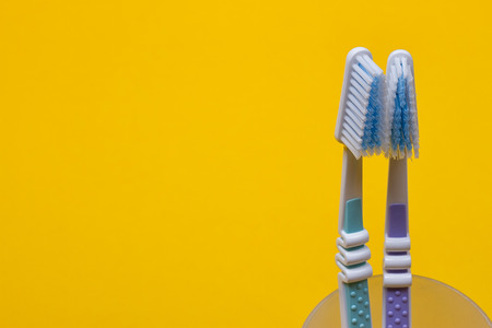 two toothbrushes in a glass on the yellow background. Top viewの写真素材