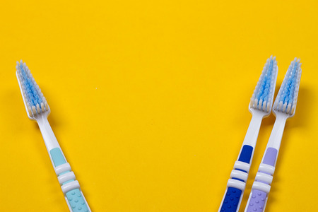 three Toothbrushes on the yellow background. Top viewの写真素材