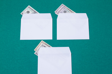three white envelopes with money on green backgroundの写真素材