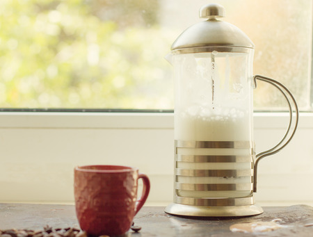 French press with whipped milk on the windowの写真素材