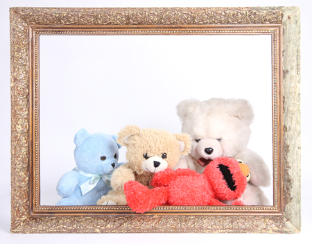 Cute teddy bears sitting behind old wooden frame