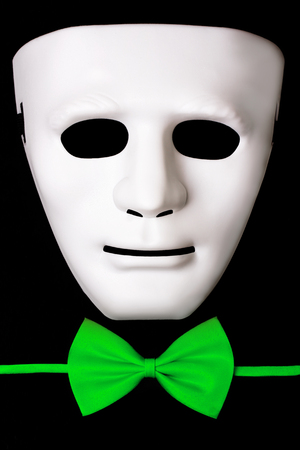 White mask and green bow tie isolated on black backgroundの写真素材