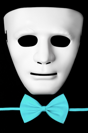 White mask and blue bow tie isolated on black backgroundの写真素材