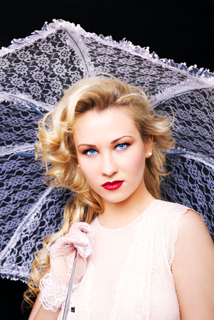 Young gorgeous blonde woman with white umbrella on a dark backgroundの写真素材