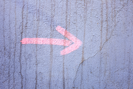 A pink arrow points to the right painted on a grunge stucco wall outsideの写真素材