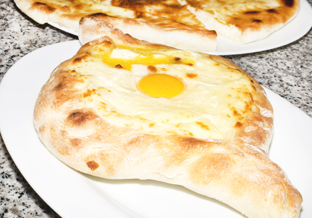 Traditional dish of georgian cuisine filled with cheese and topped with a raw egg and butter (Ajarian or Adjaruli khachapuri)の写真素材