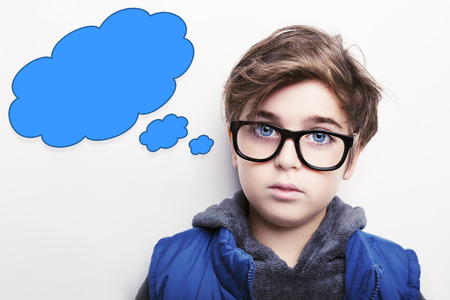 Thoughtful young boy wearing glasses with an empty thought bubbleの写真素材