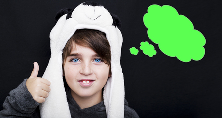 Handsome boy in panda hat giving thumbs up sign with an empty thought bubble on black background.の写真素材