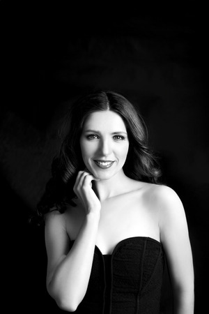 Portrait of beautiful woman in black dress with curly hair - isolated on black background.の写真素材