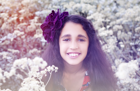 Cute little girl in spring park with first white wild flowers.の写真素材