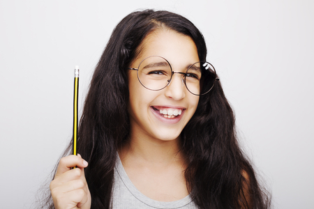 A beautiful African kid girl in glasses holding pencil in handの写真素材