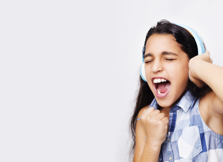 Afro-American little girl with headphones listening to music on white backgroundの写真素材