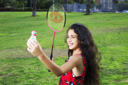 Active girl playing badminton in outdoor court in summerの写真素材