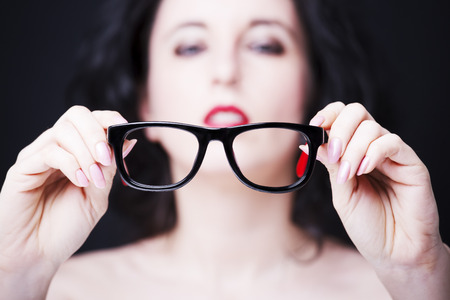 Image of a young woman holding eyeglasses.の写真素材