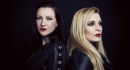 Two beautiful sexy women in leather jacket  on black backgroundの写真素材