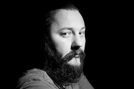 Young handsome bearded man with long beard moustache and brunette hair in studio