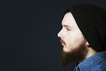 Studio portrait of caucasian young man standing up on dark backgroundの写真素材